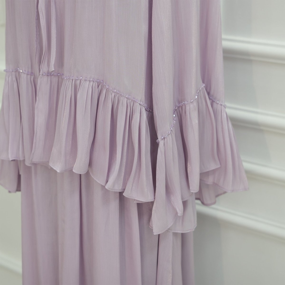 Side view of open-front cape draping over the pleated inner dress