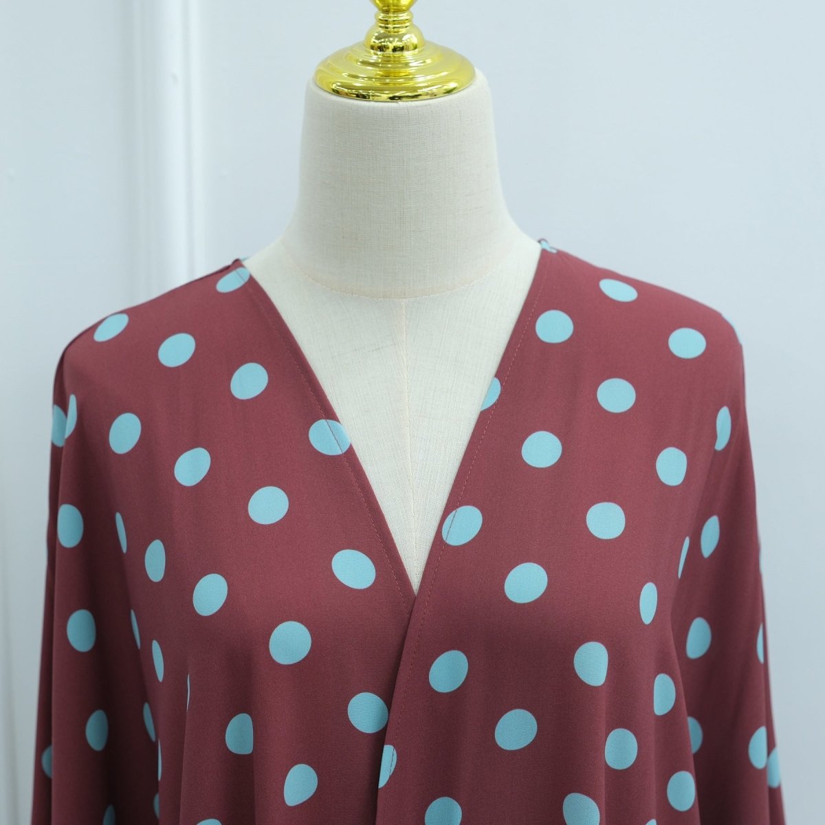 Side profile of model in flowing polka dot open abaya set