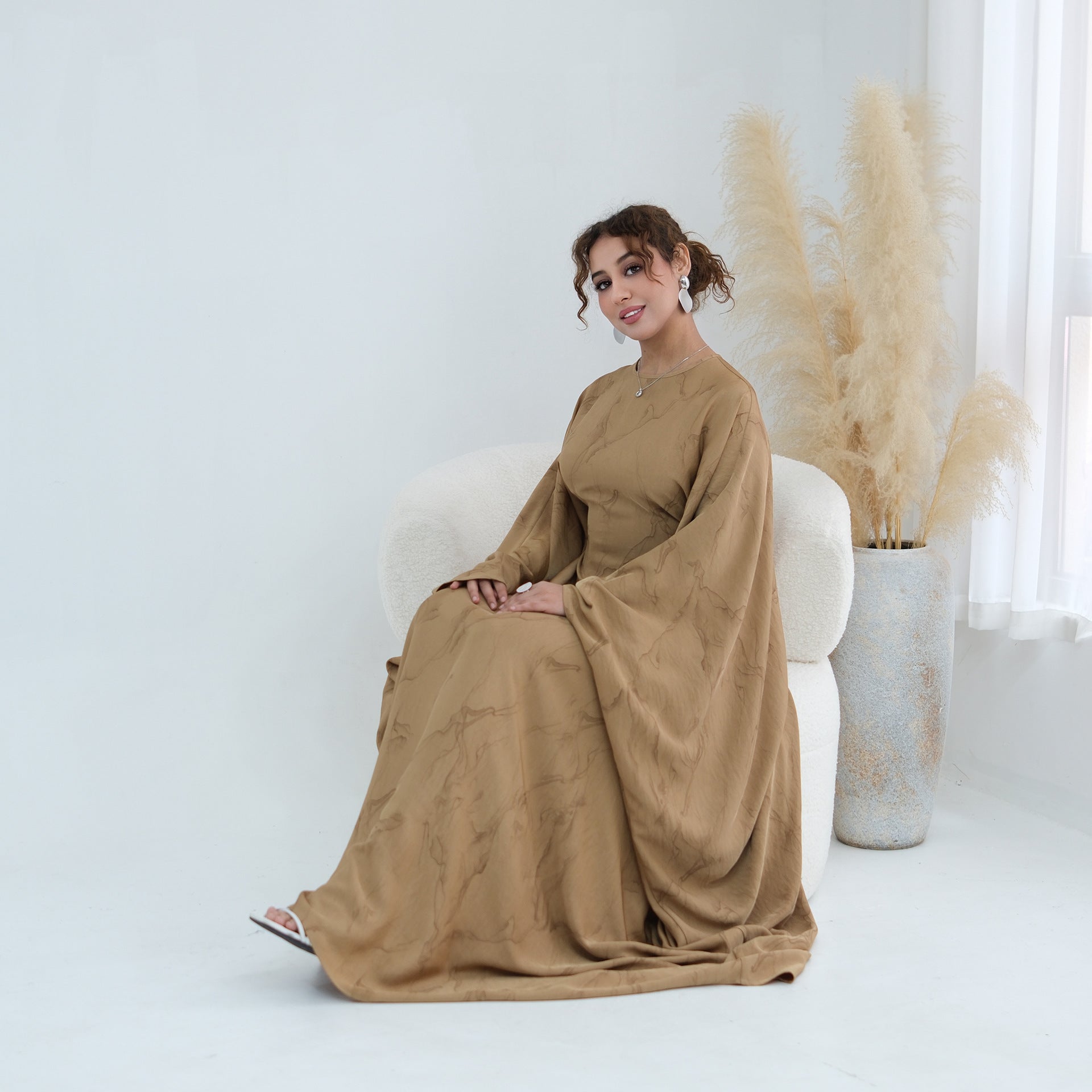 Side view of oversized batwing silhouette in flowing semi-sheer fabric
