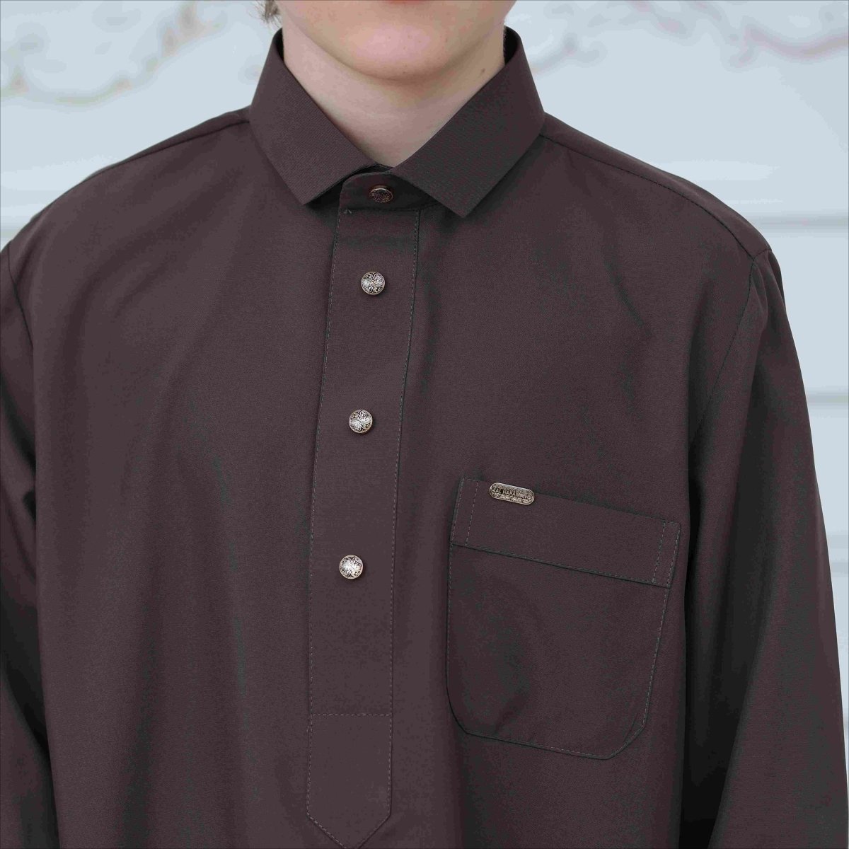 Chest pocket detail with decorative metal badge on classic kids thobe