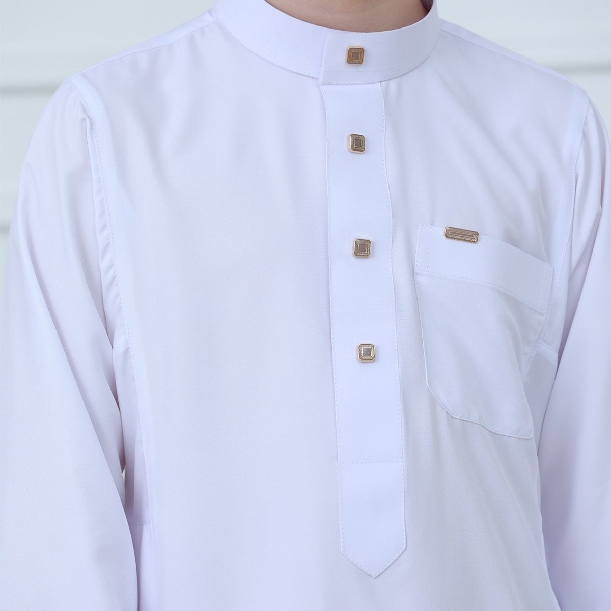 Close-up of gold-tone square buttons and placket on white boys thobe