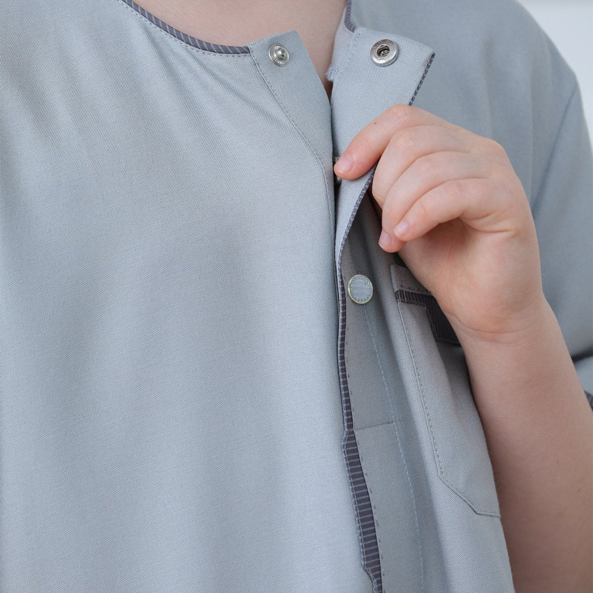 Chest pocket detail with charcoal piping on boys' powder blue poly-cotton thobe