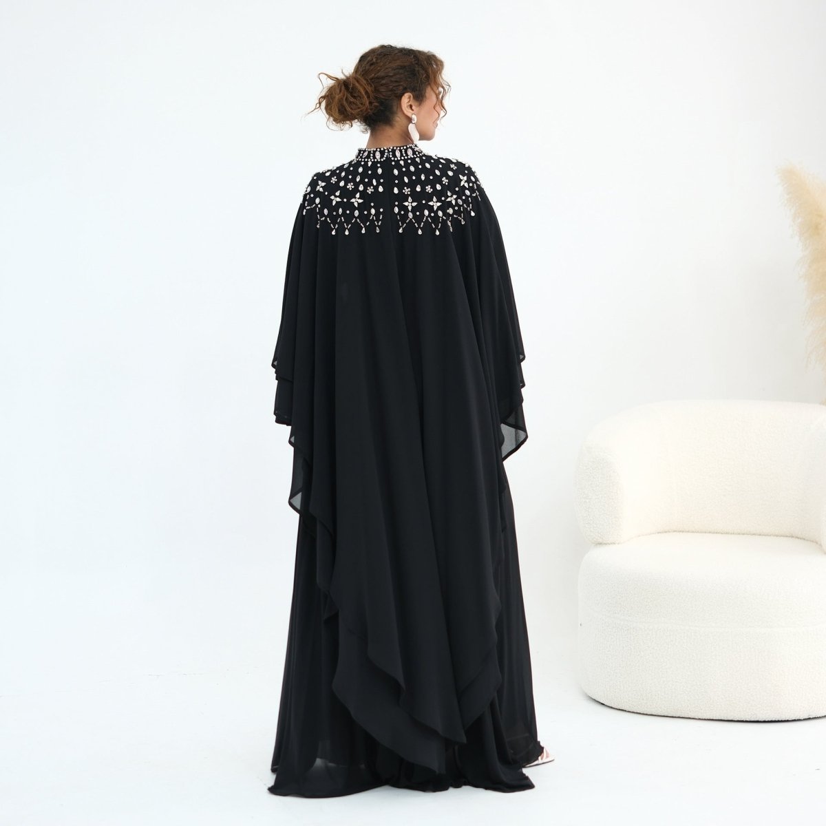 Walking movement shot showing cape sleeve sweep and floor-length hem