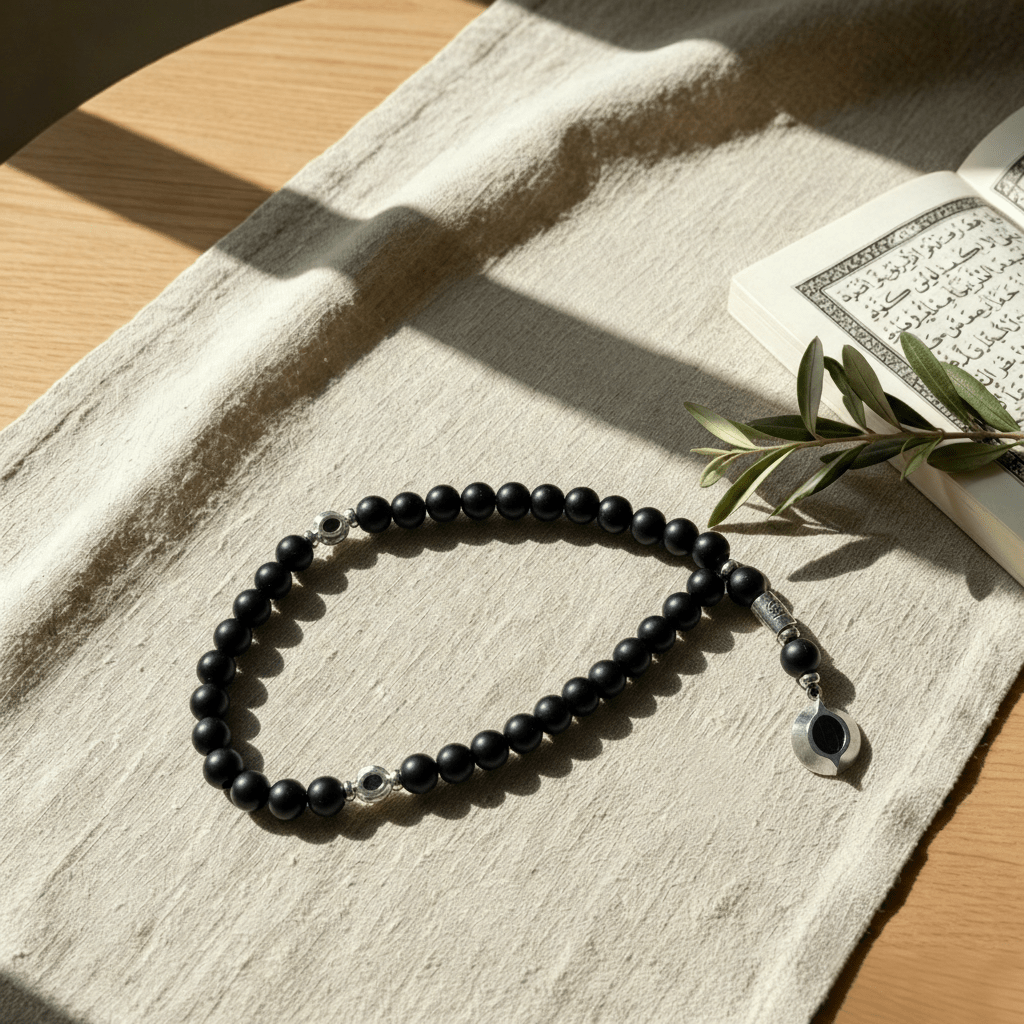 Close-up of silver openwork eye pendant and engraved metal Imame on matte black obsidian Tasbeeh