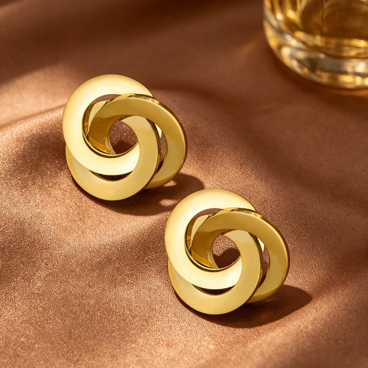 Close-up of polished interlocking triple ring knot detail on gold stud earrings