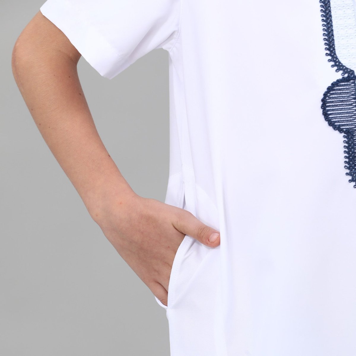 Detail shot of scroll embroidery on boys' thobe collar in cream