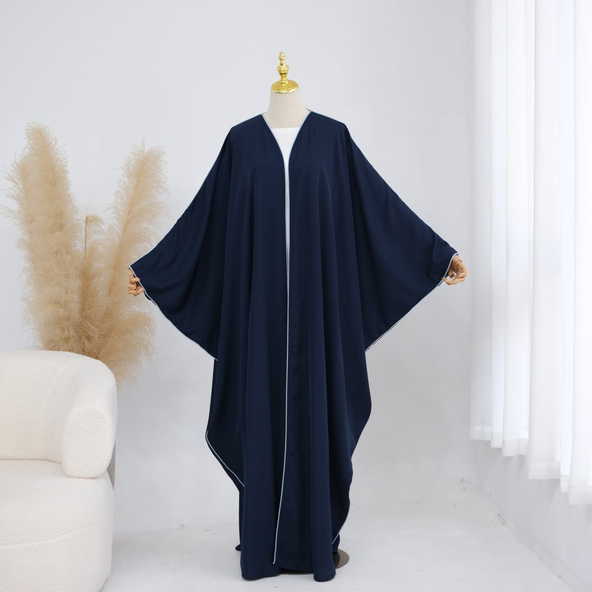 Side view of contrast piped batwing open abaya showing full-length hem