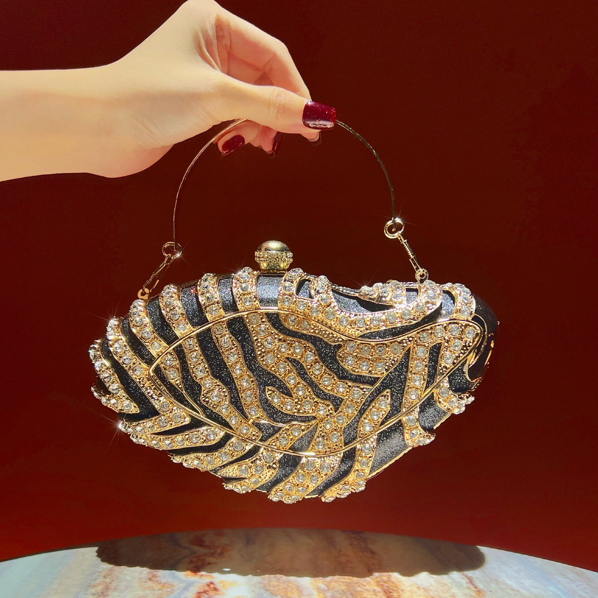 Side profile of the rhinestone top-handle clutch showing metallic clasp and chain strap