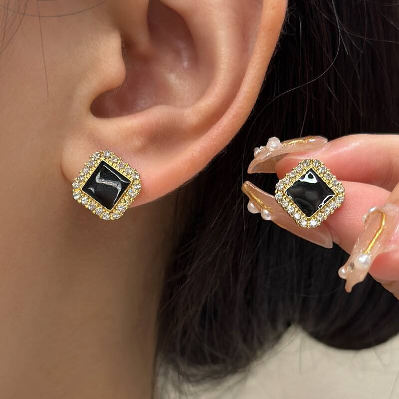Lifestyle detail of square pearl stud earrings worn at the earlobe