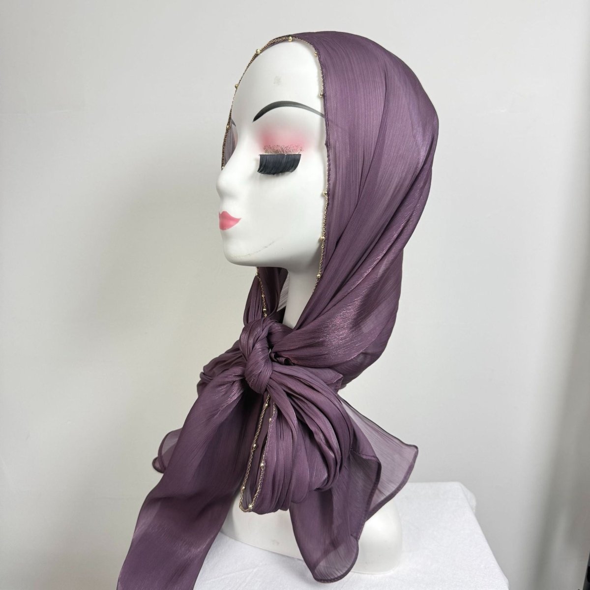Soft neutral crinkle satin hijab draped over one shoulder as decorative wrap