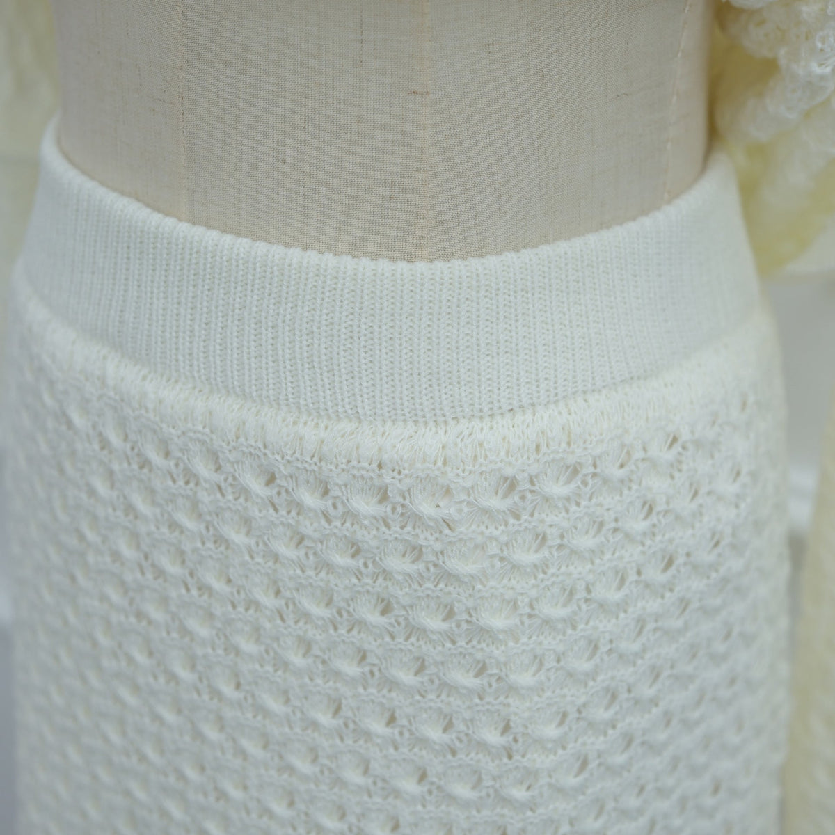 Close-up of open-stitch crochet texture on modest knitwear set