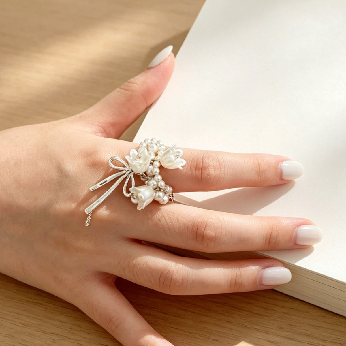 Adjustable open-band ring resting on fabric — lightweight floral jewellery detail