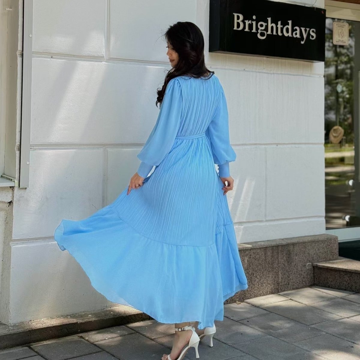 Full-length shot of tiered swing maxi dress catching light on pleated surface