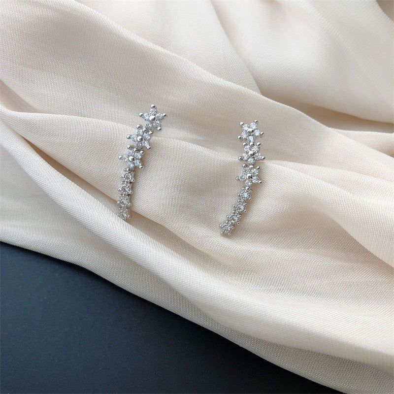 Overhead flat-lay of constellation ear crawler studs on white background