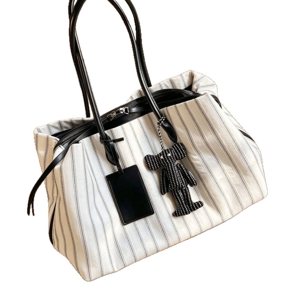 Model carrying slouchy striped work tote bag on shoulder