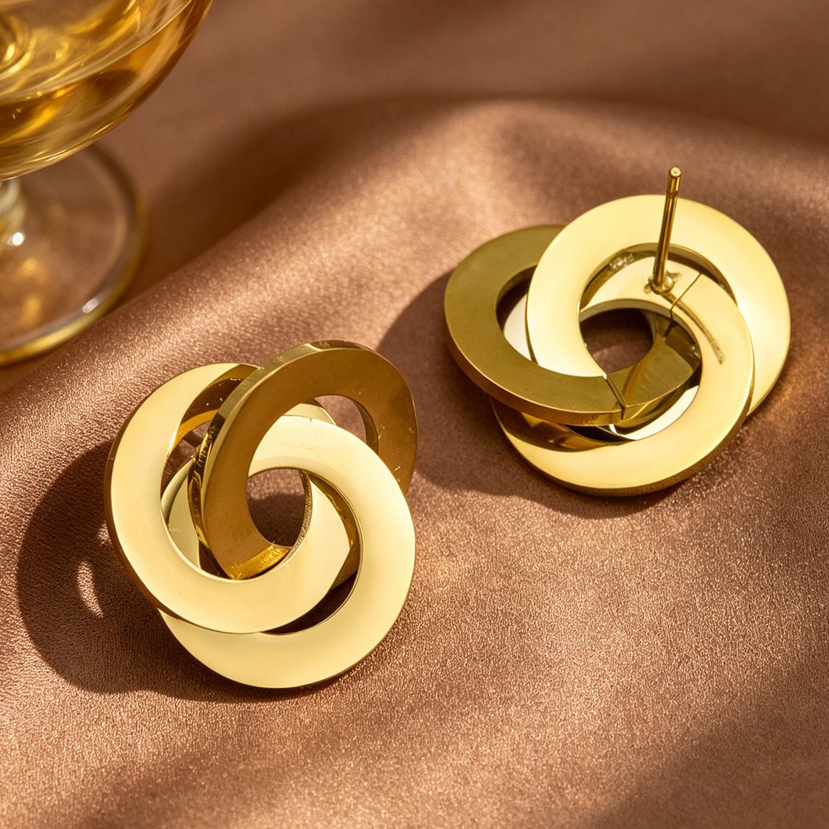 Side profile view of sculptural triple hoop stud earrings showing dimensional twist silhouette